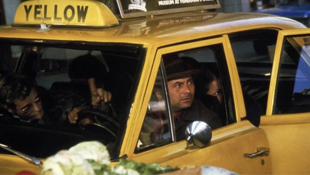 Burt Young som sitter i Taxi med Bo Hopkins i actionfilmen The Killer Elite