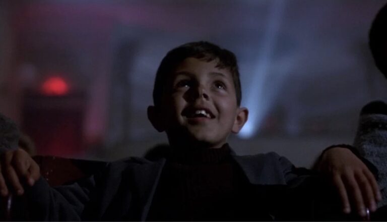 Ein gut sitt og ser på film i kinoen frå filmen Cinema Paradiso (1988)