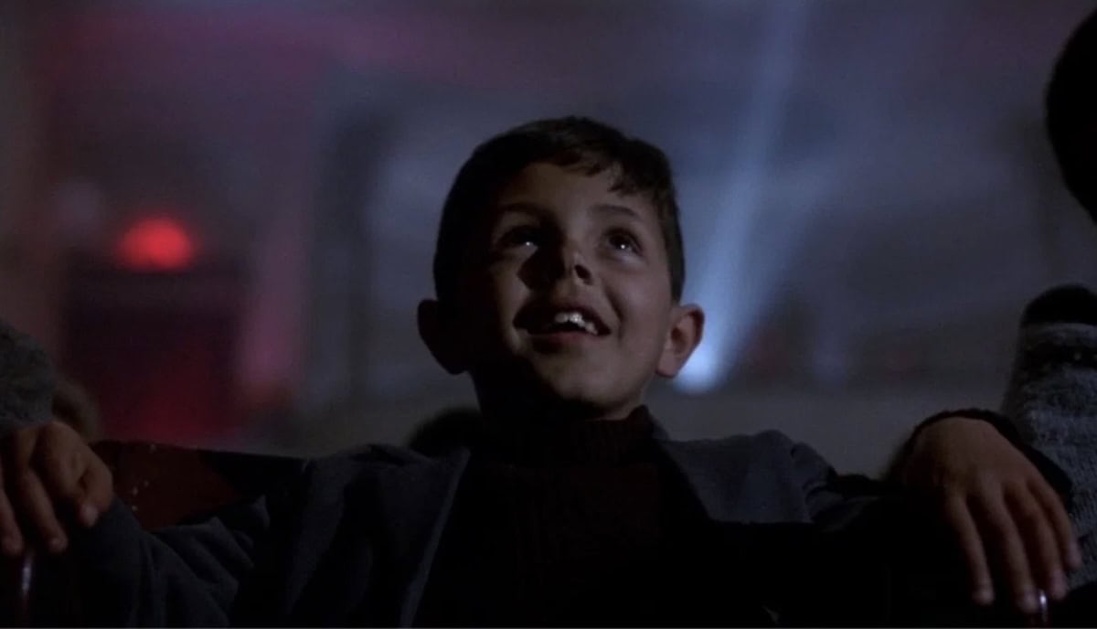 Ein gut sitt og ser på film i kinoen frå filmen Cinema Paradiso (1988)