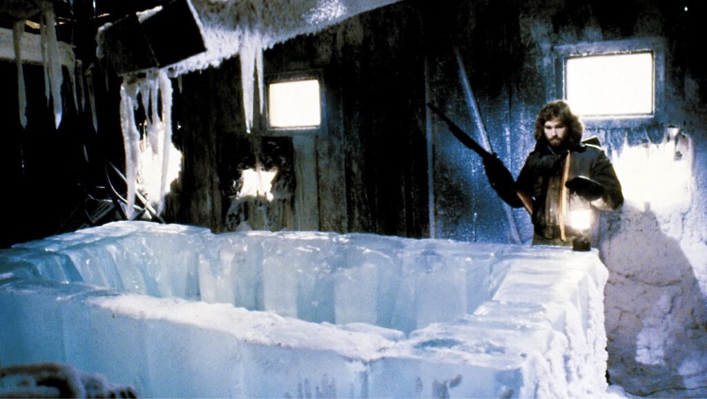 Kurt Russell som MacReady foran ei open isgrav. Frå filmen The Thing (1982)