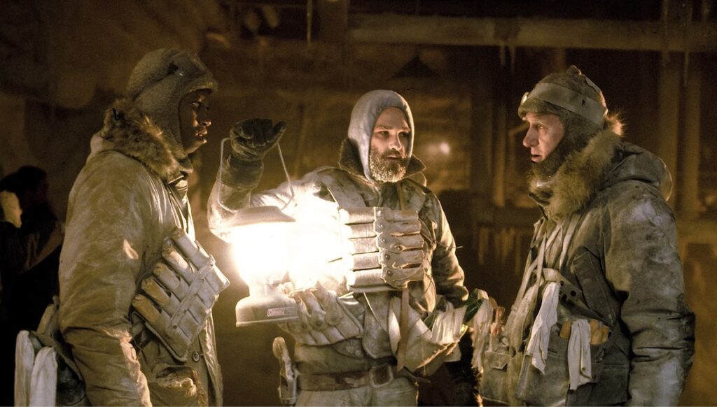 MacReady står med sine kollegaer med kulde overalt. Frå John Carpenters The Thing (1982).