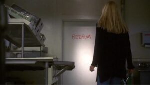 Rebecca De Mornay står med ryggen til og les orda "Redrum" frå miniserien The Shining (1997)